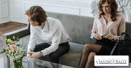 couple sitting far apart on couch, man looking into distance and woman in thought