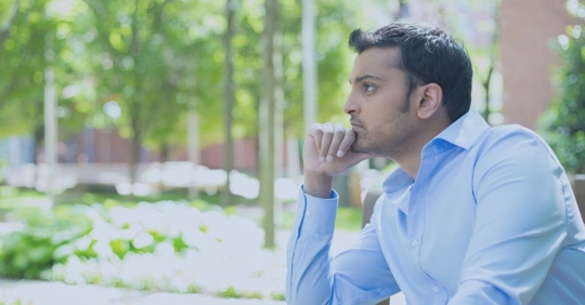 A man with his hand on his chin looking into the distance